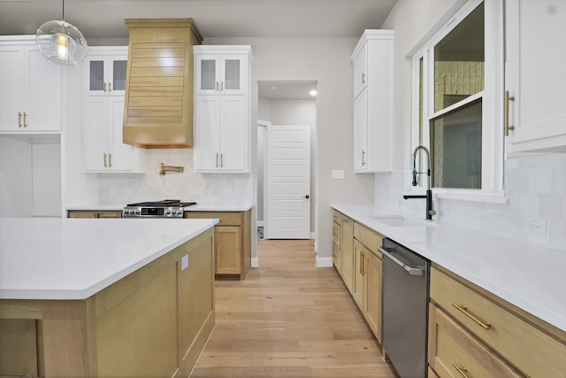 kitchen with white cabinets, sink, decorative light fixtures, stainless steel appliances, and light hardwood / wood-style floors