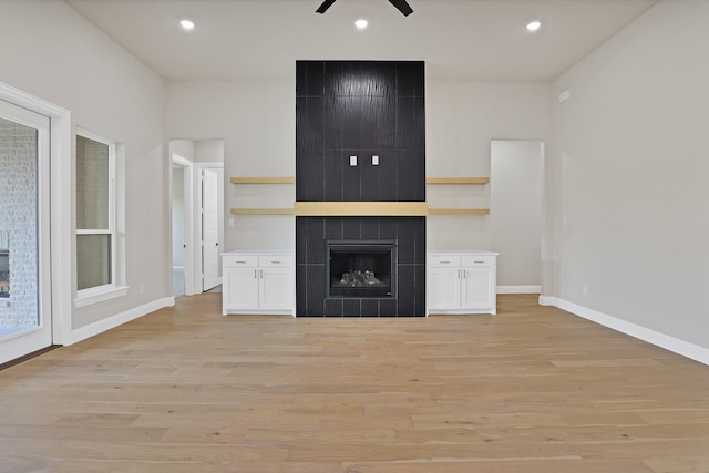 unfurnished living room featuring ceiling fan, light wood-type flooring, and a tiled fireplace