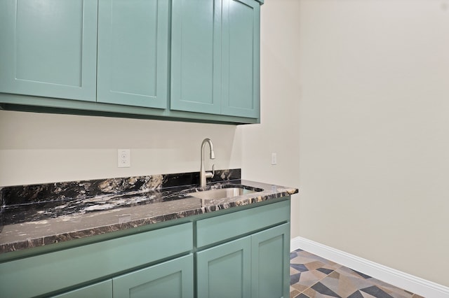 kitchen featuring dark stone counters, green cabinets, and sink