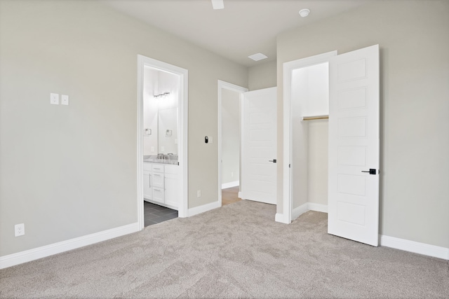 unfurnished bedroom featuring carpet floors, a walk in closet, ceiling fan, a closet, and ensuite bath