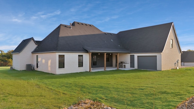 back of property with central air condition unit, a yard, a patio area, and a garage