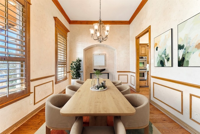 dining room with an inviting chandelier, ornamental molding, and hardwood / wood-style flooring