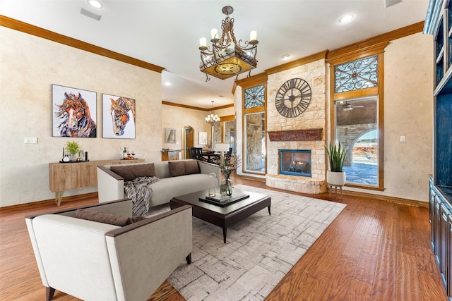 living room featuring ceiling fan with notable chandelier, hardwood / wood-style floors, crown molding, and a fireplace