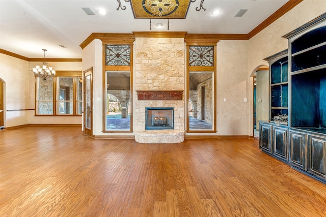 unfurnished living room featuring a fireplace, a chandelier, crown molding, and hardwood / wood-style flooring