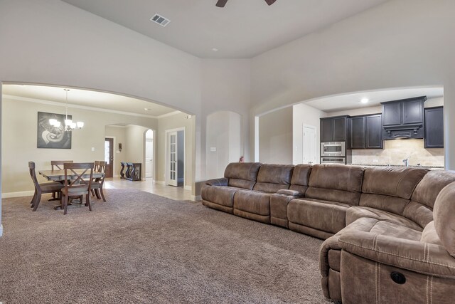 living room with ceiling fan with notable chandelier, ornamental molding, and light carpet