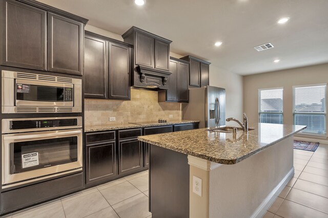 kitchen featuring decorative backsplash, sink, stainless steel appliances, and a center island with sink