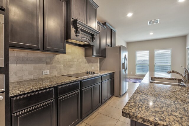 kitchen with premium range hood, black electric cooktop, tasteful backsplash, sink, and dark stone counters