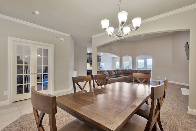 tiled dining space with a notable chandelier, ornamental molding, and french doors