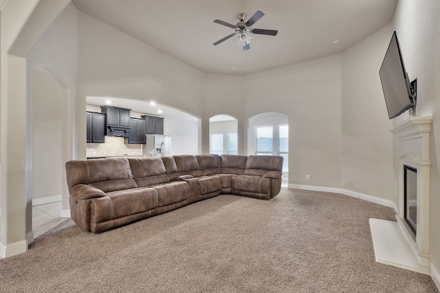 living room featuring high vaulted ceiling, ceiling fan, and light colored carpet