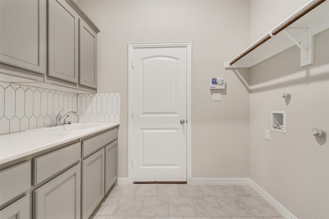 laundry area featuring sink, washer hookup, cabinets, and light tile patterned flooring