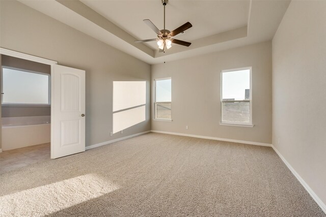 carpeted spare room featuring ceiling fan and a tray ceiling