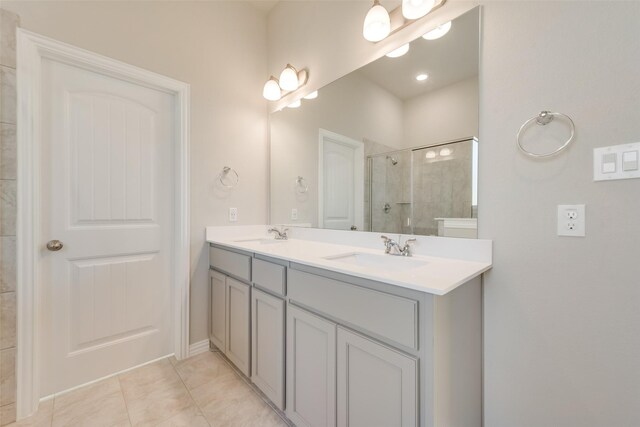 bathroom featuring a shower with door, double sink vanity, and tile patterned floors