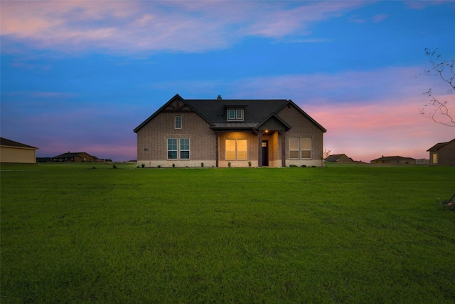 view of front of house featuring a standing seam roof, brick siding, a lawn, and metal roof