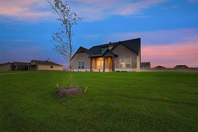 view of front of home with a yard and brick siding