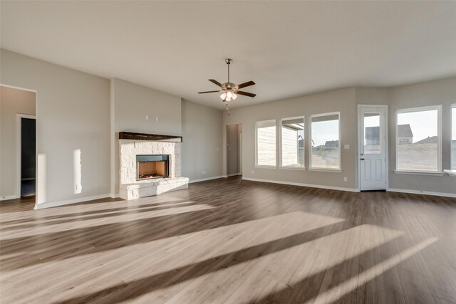 unfurnished living room featuring hardwood / wood-style floors, ceiling fan, and a fireplace