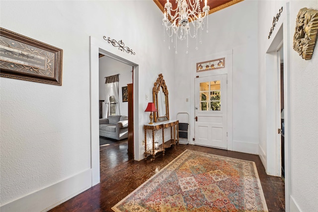 foyer with dark hardwood / wood-style flooring, an inviting chandelier, and a high ceiling