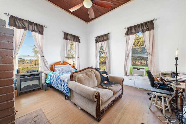 bedroom with ceiling fan, multiple windows, cooling unit, and hardwood / wood-style flooring