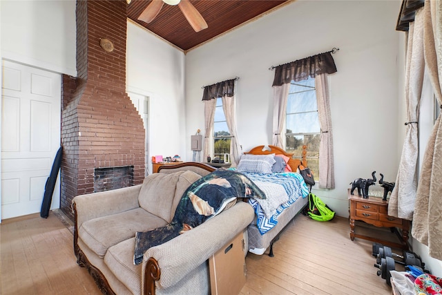 bedroom with ornamental molding, a brick fireplace, hardwood / wood-style flooring, ceiling fan, and brick wall