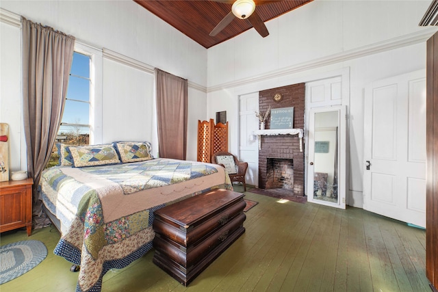 bedroom featuring hardwood / wood-style flooring, a fireplace, and ceiling fan