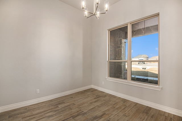 spare room with a chandelier and dark hardwood / wood-style flooring