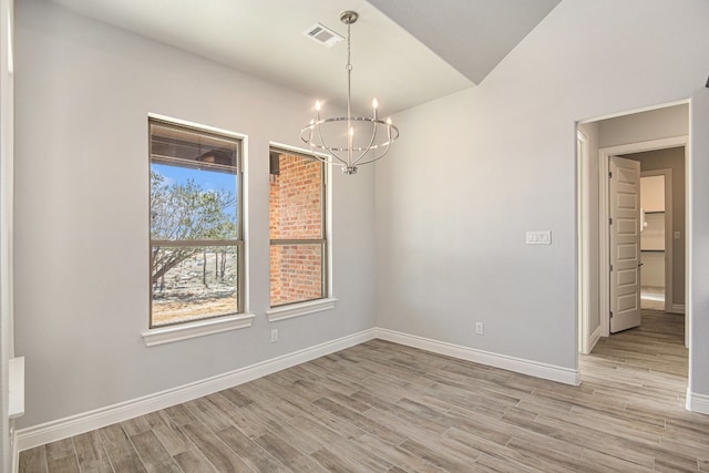 unfurnished dining area with light hardwood / wood-style floors and an inviting chandelier