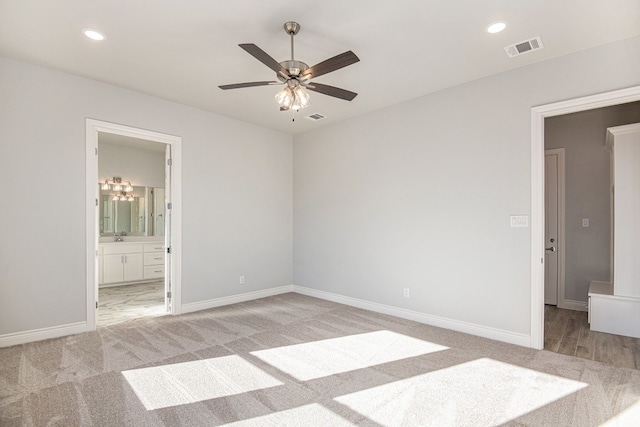 unfurnished bedroom featuring light carpet, ensuite bath, and ceiling fan