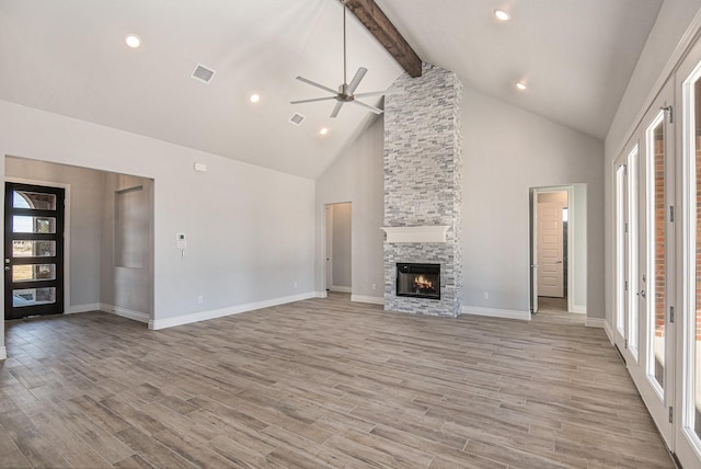 unfurnished living room featuring beamed ceiling, a fireplace, ceiling fan, light wood-type flooring, and high vaulted ceiling