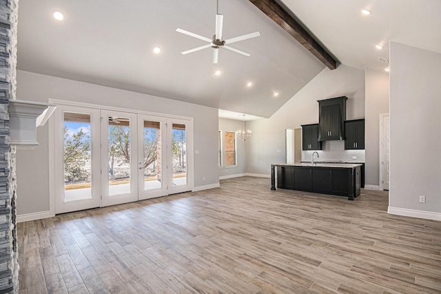 unfurnished living room with sink, ceiling fan with notable chandelier, high vaulted ceiling, and beam ceiling