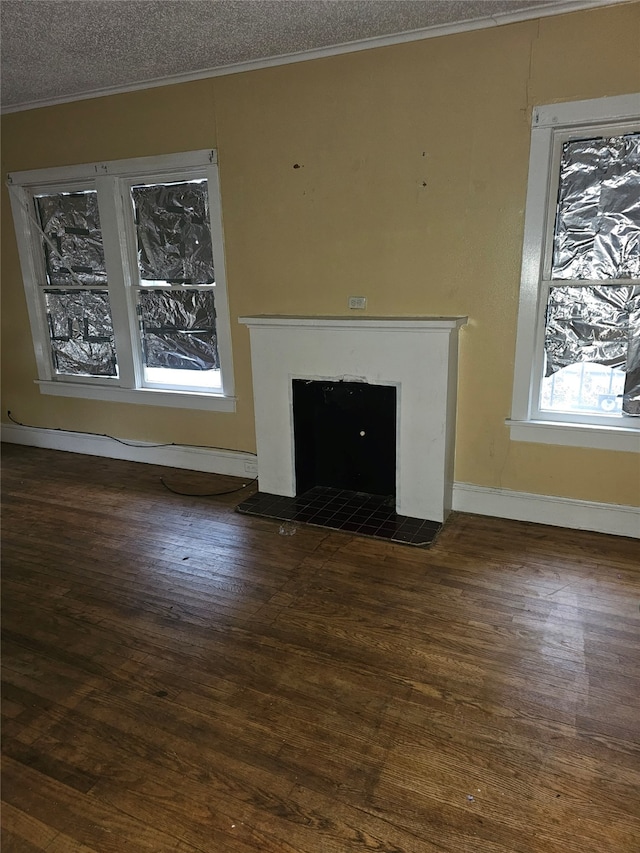 unfurnished living room with a fireplace, a textured ceiling, ornamental molding, and wood-type flooring