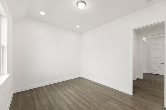 spare room featuring lofted ceiling and dark hardwood / wood-style floors