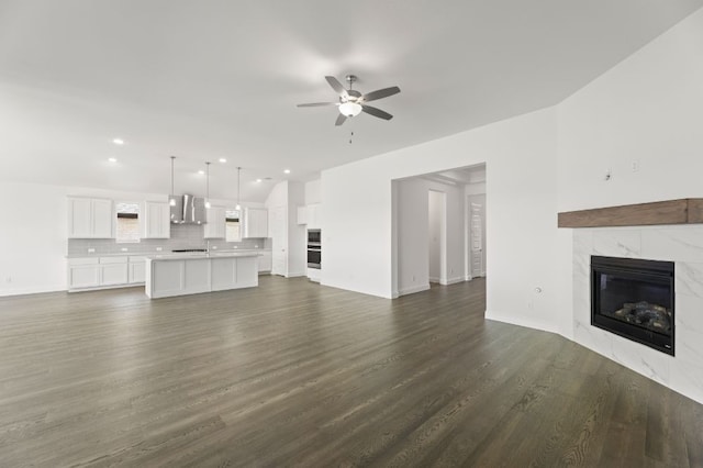 unfurnished living room with ceiling fan, dark hardwood / wood-style floors, and a tile fireplace