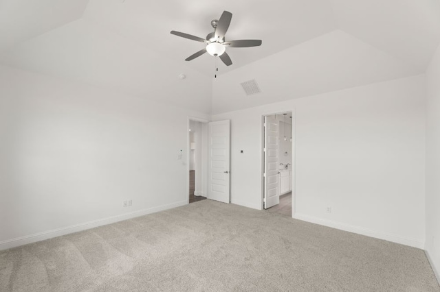 unfurnished bedroom featuring ceiling fan, vaulted ceiling, light carpet, and ensuite bathroom