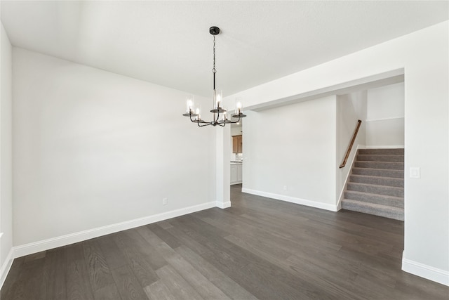 unfurnished dining area featuring dark wood-style floors, stairway, a chandelier, and baseboards