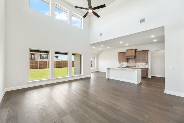 unfurnished living room featuring ceiling fan, dark wood-type flooring, visible vents, and baseboards