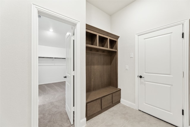 mudroom with light carpet, baseboards, and light tile patterned flooring