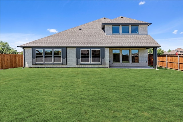 rear view of property with a fenced backyard, a lawn, and roof with shingles