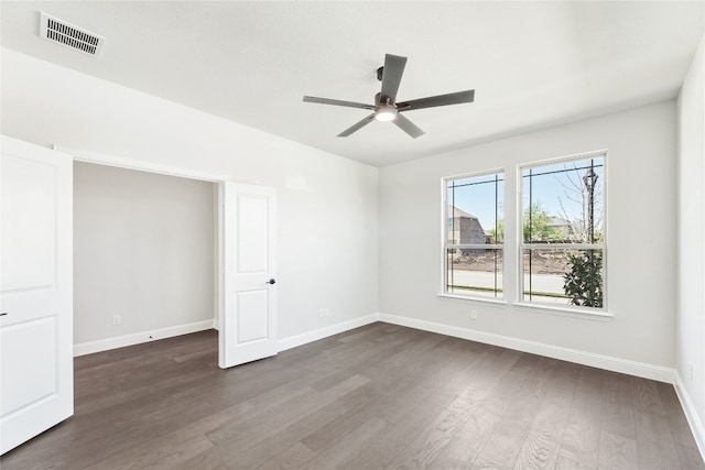 empty room featuring dark wood-style floors, baseboards, visible vents, and ceiling fan