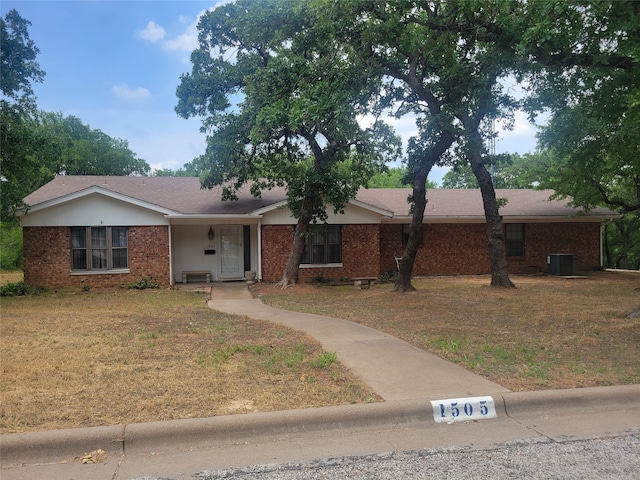 single story home with cooling unit and a front yard