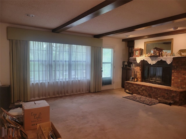 carpeted living area with a textured ceiling, beamed ceiling, and a fireplace