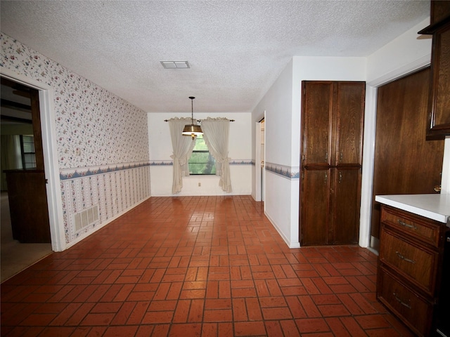 1505 S Rodgers Dr, Graham, TX 76450 - unfurnished dining area with wallpapered walls, brick patterned floors, and a textured ceiling