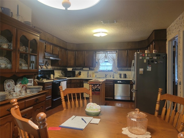 kitchen with dark brown cabinetry, black appliances, a textured ceiling, and under cabinet range hood