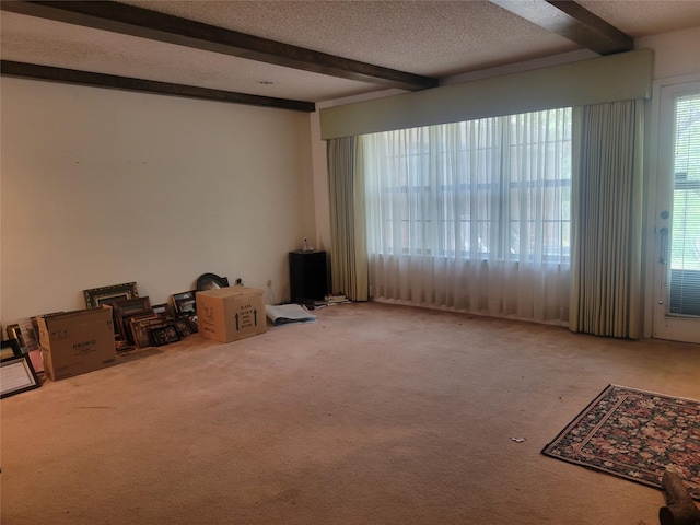 carpeted empty room with a textured ceiling and beam ceiling