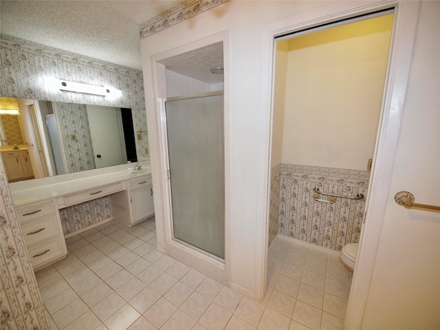 1505 S Rodgers Dr, Graham, TX 76450 - bathroom with wallpapered walls, tile patterned floors, a stall shower, toilet, and a textured ceiling