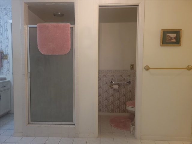 bathroom with a shower with shower door, tile patterned floors, and toilet