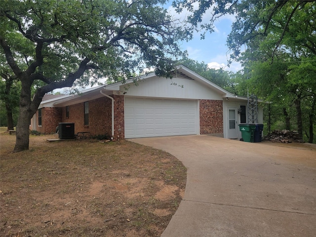 view of side of home featuring central air condition unit, brick siding, an attached garage, and driveway