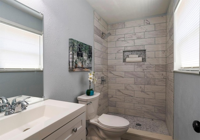 bathroom featuring toilet, vanity, and tiled shower