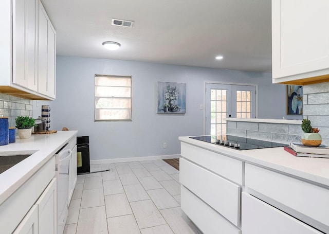 kitchen featuring light tile flooring, backsplash, black electric cooktop, white dishwasher, and white cabinetry