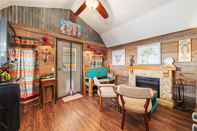 living area with a fireplace, wooden walls, dark hardwood / wood-style flooring, lofted ceiling, and ceiling fan