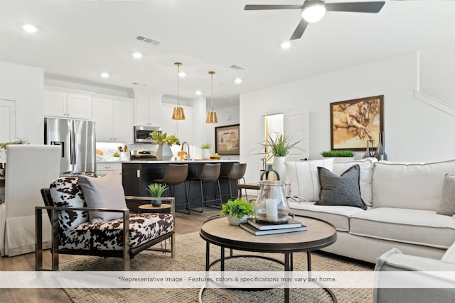 living room with ceiling fan, light wood-type flooring, and sink