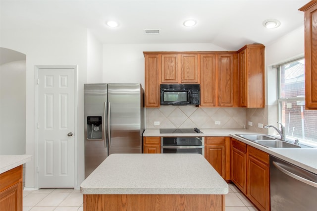 kitchen featuring tasteful backsplash, sink, black appliances, light tile patterned floors, and a kitchen island